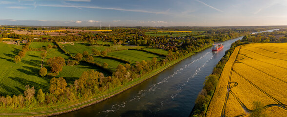 cargo ship on the kiel canal with flourishing agriculture and renewable energy production in the bac