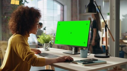 Fototapete - Creative Multiethnic Female Working on Desktop Computer with Green Screen Mock Up Display. Happy Project Manager Browsing Internet, Writing Tasks, Developing a Marketing Strategy for a Partner.