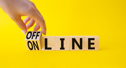 Wall Mural - Offline and online symbol. Businessman hand turnes wooden cubes and changes word Online to Offline. Beautiful yellow background. Business concept. Copy space.