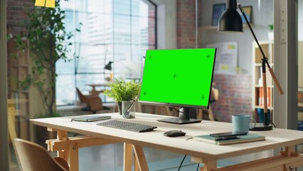 Fototapete - Establishing Shot: Desktop Computer Monitor with Green Screen Mock Up Chroma Key Display Standing on a Desk in Modern Creative Office. Cozy Agency Space in Loft Building.