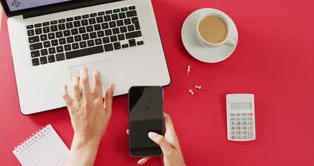Wall Mural - hands using laptop and smartphone, with coffee and calculator on red desk