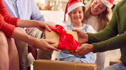 Close Up Of Multi-Generation Family Celebrating Christmas At Home Opening Presents