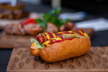 Sandwich, Hot Dog With Sausage, Mustard And Sause Ketchup On Wooden Board On Table At Outdoor Street Food Festival, Market. Gastronomy, Sale And Takeaway Food Concept