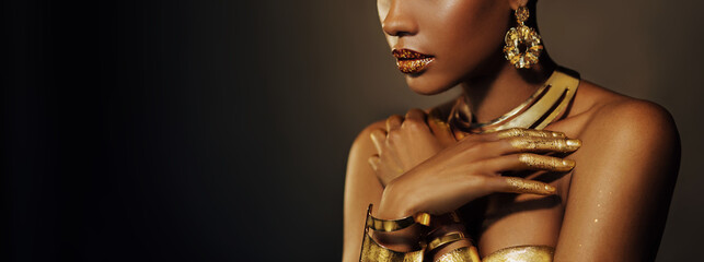 Wall Mural - Portrait Closeup Beauty fantasy african woman, face in gold paint. Golden shiny black skin. Fashion model girl mixed race. Glamorous arab turban, jewellery accessories. Professional metallic makeup