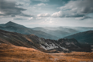 Wall Mural - wonderful alpine landscape with hill meadows and mountain range in valley with forest in autumn colo