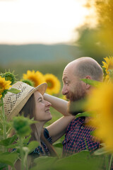 Canvas Print - Young romantic couple in sunflower field in sunset