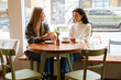 © Drobot Dean - Two young women smiling and drinking tea while sitting at cafe