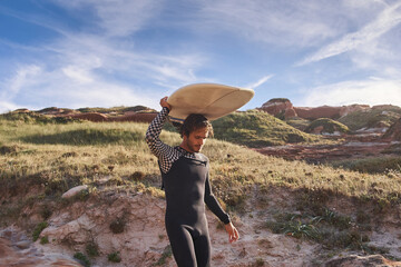 Wall Mural - Active sporty man carrying his surfboard on the head