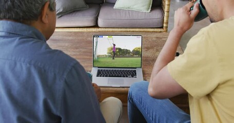 Canvas Print - Video of father and son sitting on the couch and watching football match on laptop