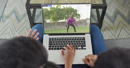 Wall Mural - Video of two african american people sitting on the couch and watching football match on laptop