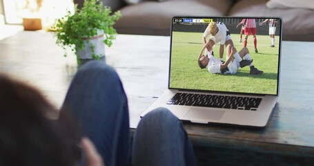 Canvas Print - Video of person sitting on the couch and watching football match on laptop