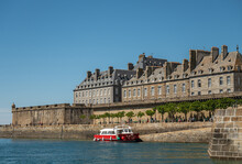 St. Malo, Brittany, France - July 8, 2022: Small Red Ferry Docked At Quai De Dinan With Bastion Saint Philippe On Front Corner Under Blue Sky. Pedestrians Around.