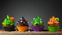 Cupcake On Halloween. Pumpkin Jack O Lantern. Dessert On Halloween Party. Muffin Decorated With Colored Sprinkles, Frosting And Icing Shaped Pumpkin Jack-o-lantern. Cupcakes On Dark Background. 