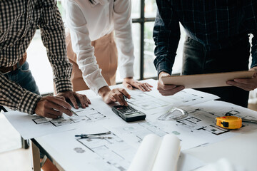 Close up of hands working brainstorming and measuring for cost estimating on paperworks and floor plan drawings about design architectural and engineering for houses and buildings.