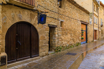 Poster - Old wooden gate with metal accents in an old stone house facade in Olite, Spain