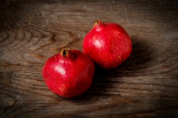 Closeup of two pomegranates against a wooden background