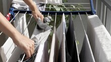 Woman Hanging Wet Clean Cloth On Laundry Drying Rack In Balkony At Home. Close Up Of Female Hands Hanging Washed Clothes, Towels, Linens On Clothes Wire Dryer