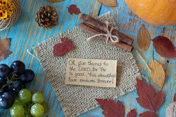 Wall Mural - Handwritten text note to give thanks to the LORD on vintage wooden autumn background with grapes, pumpkin, and dry leaves. Christian thanksgiving, gratitude, and praise to God. Top table view.