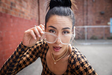 Asian Woman Looking Over Her Eye Glasses With An Expression Of Skepticism. 