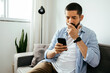 © kleberpicui - Sad man checking smartphone sitting on a sofa at home