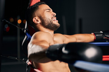 Poster - Boxing, pain and tired boxer in the ring fighting in a sports arena or stadium for a competitive championship. Fitness, exercise and intense training workout by a young Latino fighter with an injury