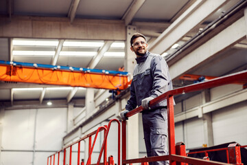 Wall Mural - A factory worker stands and leans on the railing and monitors the works in the facility.