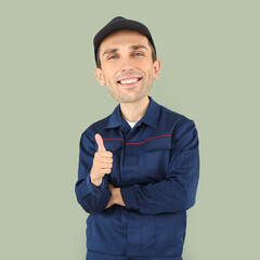 Wall Mural - Funny car mechanic with big head showing thumb-up on color background