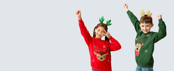 Dancing little children with reindeer horns on light background with space for text