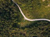 Fototapeta Uliczki - Top down aerial drone view of the road in mountain range trough the trees and forest wild travel rural vacation and nature concept background