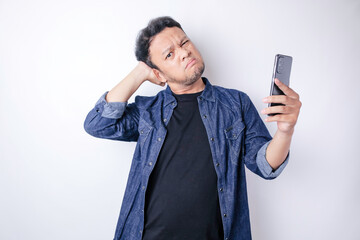 A portrait of an Asian man wearing a navy blue shirt looks so confused, isolated by a white background