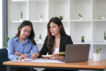 Two Young Asian businesswoman discuss with new startup project Idea presentation, analyze planning and financial statistics and investment market at office.