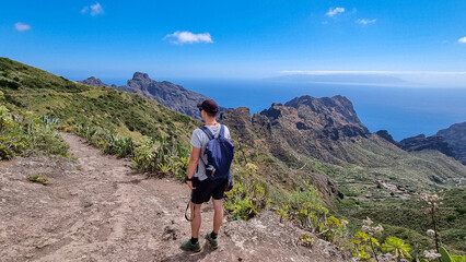 rear view on man on scenic hiking trail near masca in teno mountain massif, tenerife, canary islands