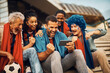 © Drazen - Group of excited fans watching live broadcast of soccer match on smart phone.