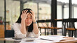 © Prathankarnpap - Tired office worker holding her head, feeling strong headache, exhausted from overwork or stress at work