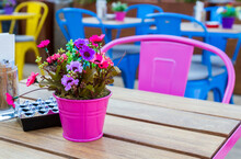 Close-up View Of Metal Pot With Artificial Flowers On The Table In Outdoor Restaurant