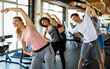 © NDABCREATIVITY - Group of fit people working out in a gym. Multiracial friends exercising together in fitness club.