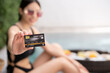 © marchsirawit - Woman show credit card with floating breakfast in the pool on luxury villa, payment luxury travel.