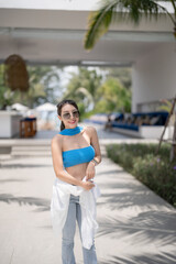 Wall Mural - Woman in blue top and jeans walking in tropical resort hotel.