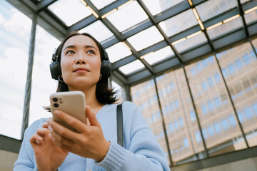 Wall Mural - young woman wearing headphones and using mobile phone at subway station