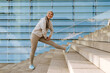 © Drobot Dean - Asian woman in tracksuit smiling and doing workout on stairs outdoors