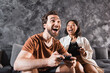 © LIGHTFIELD STUDIOS - KYIV, UKRAINE - JULY 26, 2022: excited man holding joystick and playing video game with bi-racial woman in living room