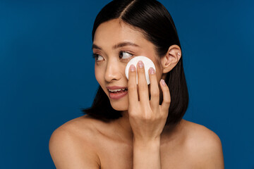 Wall Mural - Young beautiful asian woman wiping her face with cotton pad