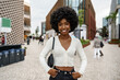 © fotofabrika - Portrait of young african woman with hairstyle smiling in urban background