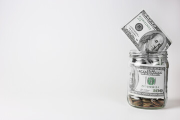 Dollars in a glass jar with coins on a white background. Money saving concept