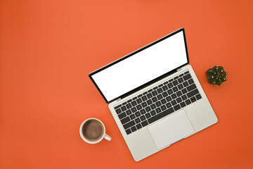 Poster - Top view of Creative office desk concept, Laptop with empty screen, coffee cup on the orange background.