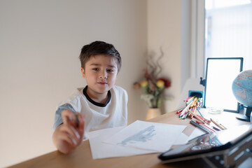 Wall Mural - School kid using grey colour pen drawing or sketching on paper,Portrait  boy siting alone and looking out with thinking face, ,Child enjoy art and craft activity at home on weekend,Education concept