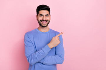 Wall Mural - Photo of attractive cheerful arab guy dressed blue pullover pointing empty space isolated pink color background