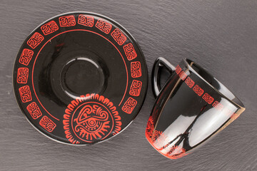 Poster - One black ceramic coffee cup with saucer on slate stone, close-up, top view.