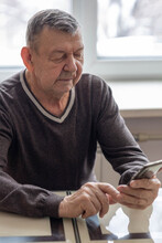 Elderly Man Dials Number In Smartphone From Home. Old Senior Sends Sms On Mobile Phone