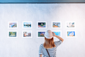 Woman visiting art gallery her looking pictures on wall watching photo frame painting at artwork museum people lifestyle concept.